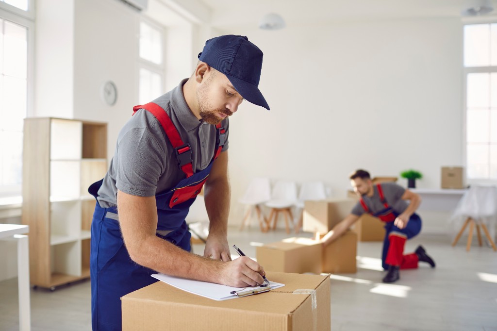 Mover documenting packed boxes with a clipboard