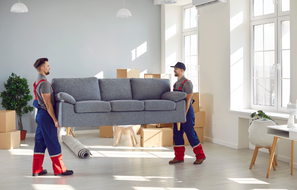 Local movers carrying a sofa inside a home